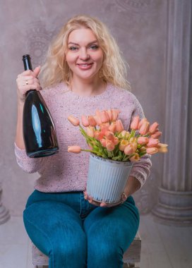 Nice happy woman celebrate with bottle of Champaign and flowers. Happy mood