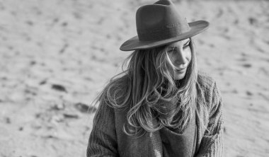 Woman in wool yellow cardigan, fedora hat and blue jeans at the beach, new collection, fashionable trend