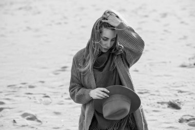Woman in wool yellow cardigan, fedora hat and blue jeans at the beach, new collection, fashionable trend
