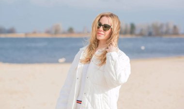 Beyaz ceketli kadın, güneş gözlüğü ve kumsalda kot pantolon, yeni koleksiyon, modaya uygun moda.