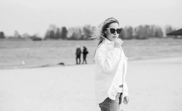 海滩上穿着白色夹克 太阳镜和蓝色牛仔裤的女人 新系列 时尚潮流 — 图库照片