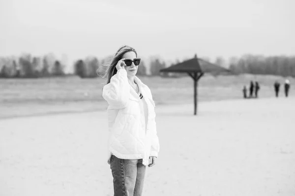 ビーチで白いジャケット サングラス 青いジーンズの女性 新しいコレクション ファッショナブルなトレンド — ストック写真