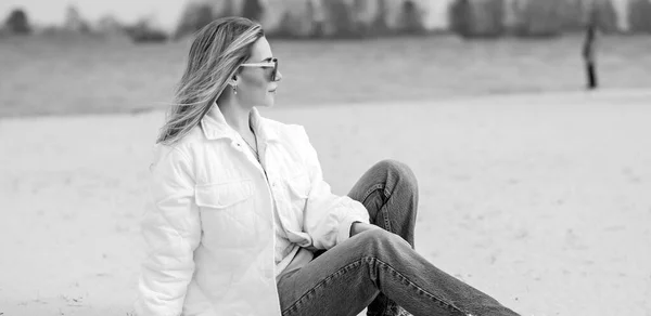 Kobieta Białej Kurtce Okulary Przeciwsłoneczne Niebieskie Dżinsy Plaży Nowa Kolekcja — Zdjęcie stockowe