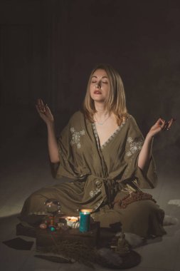 Kadın sunakla oturur, mumların arasında sihir, temiz negatif enerji, reiki oturumu, wicca konsepti