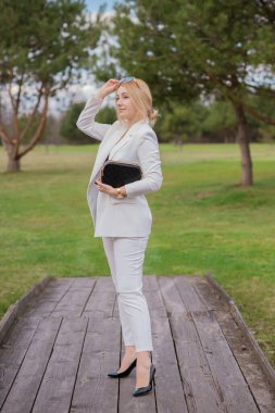 Beyaz takım elbiseli, şık giyinmiş, iş kıyafeti giymiş bir iş kadını. Modern lades yaşam tarzı kavramı