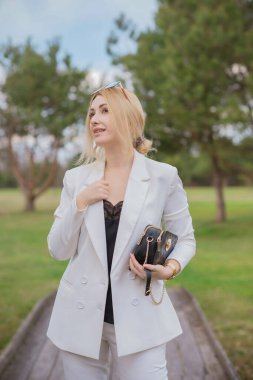 Beyaz takım elbiseli, şık giyinmiş, iş kıyafeti giymiş bir iş kadını. Modern lades yaşam tarzı kavramı