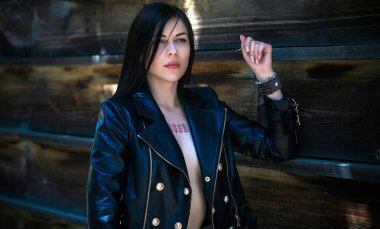 Grunge tarzı, siyah uzun saçlı, deri ceketli, güzel, seksi genç bir kadın. 90 'ların biçimi