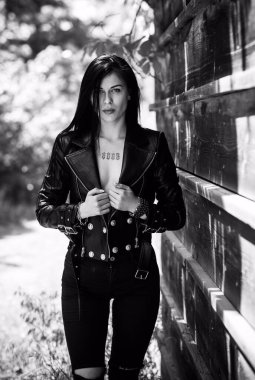 Grunge tarzı, siyah uzun saçlı, deri ceketli, güzel, seksi genç bir kadın. 90 'ların biçimi