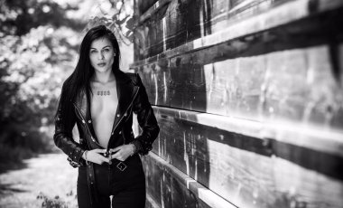 Grunge tarzı, siyah uzun saçlı, deri ceketli, güzel, seksi genç bir kadın. 90 'ların biçimi