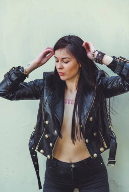 Grunge tarzı, siyah uzun saçlı, deri ceketli, güzel, seksi genç bir kadın. 90 'ların biçimi