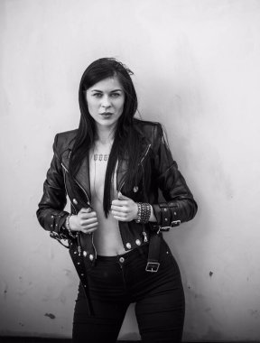 Grunge tarzı, siyah uzun saçlı, deri ceketli, güzel, seksi genç bir kadın. 90 'ların biçimi