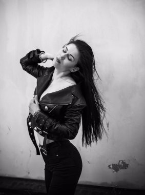 Grunge tarzı, siyah uzun saçlı, deri ceketli, güzel, seksi genç bir kadın. 90 'ların biçimi
