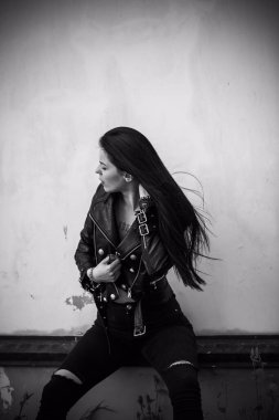 Grunge tarzı, siyah uzun saçlı, deri ceketli, güzel, seksi genç bir kadın. 90 'ların biçimi