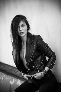 Grunge tarzı, siyah uzun saçlı, deri ceketli, güzel, seksi genç bir kadın. 90 'ların biçimi