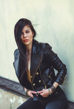 Grunge tarzı, siyah uzun saçlı, deri ceketli, güzel, seksi genç bir kadın. 90 'ların biçimi