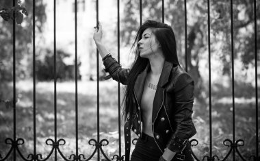 Grunge tarzı, siyah uzun saçlı, deri ceketli, güzel, seksi genç bir kadın. 90 'ların biçimi