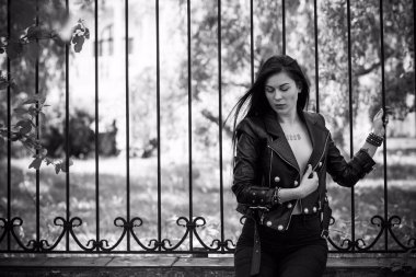 Grunge tarzı, siyah uzun saçlı, deri ceketli, güzel, seksi genç bir kadın. 90 'ların biçimi