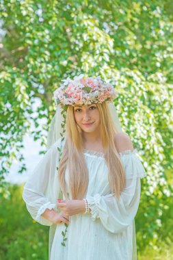 Doğadaki hassas gelin, beyaz dantelli ve çelenkli uzun sarı saçlı geleneksel Avrupalı bayan.   