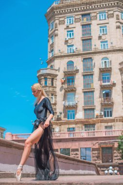 Bale kostümlü genç balerin dans ediyor ve büyük şehir hayatı ve özgürlük nefesini hissediyor.