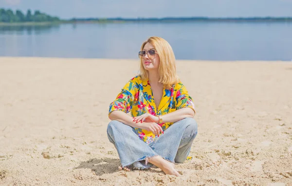 Vacation style, woman wardrobe. Illustration of young European tanned woman with blonde hair in blue jeans and colorful cotton shirt at the beach
