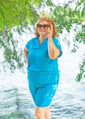 Artı mavi takım elbiseli, tatildeki boy kadın. Tatil ve hayatın tadını çıkar, olgun kadın hayatı kavramı, vücut pozitifliği.