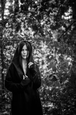 Siyah uzun saçlı, gotik tarzda siyah cüppeli bir kadın. Ormanda gizemli bir portre