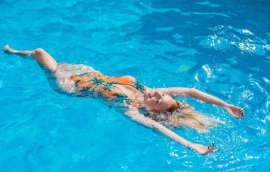Tropik tatil köyünde güzel bir rahatlama, tatil konsepti, havuzda güneşlenen güzel bir kadın.