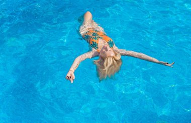 Tropik tatil köyünde güzel bir rahatlama, tatil konsepti, havuzda güneşlenen güzel bir kadın.