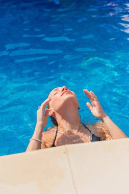 Tropik tatil köyünde güzel bir rahatlama, tatil konsepti, havuzda güneşlenen güzel bir kadın.