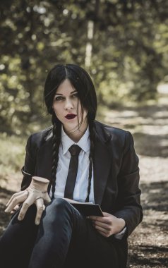 Uzun siyah örgülü gotik kız, Cadılar Bayramı partisi fikirleri, kostümlü ve ürkütücü kostümlü.