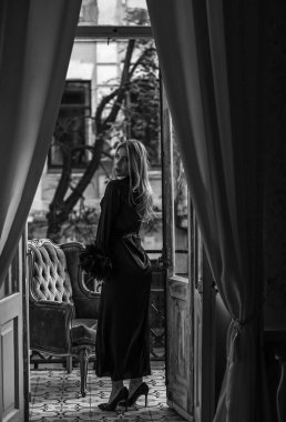 Peignoir giymiş bir kadın ve bir kadeh şarap. Tüylü siyah ipek bornozlu Avrupalı sarışın kadının şehvetli fotoğrafı. Moda konsepti