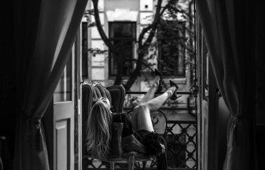 Peignoir giymiş bir kadın ve bir kadeh şarap. Tüylü siyah ipek bornozlu Avrupalı sarışın kadının şehvetli fotoğrafı. Moda konsepti