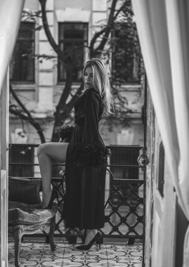 Peignoir giymiş bir kadın ve bir kadeh şarap. Tüylü siyah ipek bornozlu Avrupalı sarışın kadının şehvetli fotoğrafı. Moda konsepti