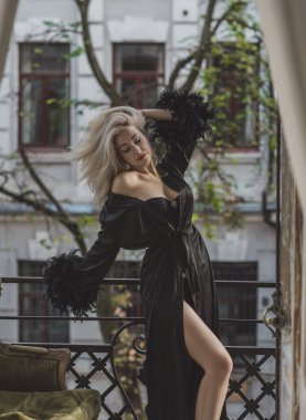 Lüks siyah ipek cüppeli, tüylü zarif sarışın kadın. Kadın kıyafetleri, her gardıropta kusursuzluk.