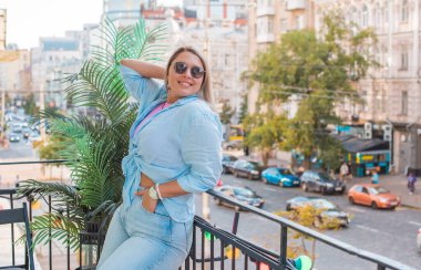 Gülümseyen Avrupalı bir model, günlük giysiler içinde, şehir arkasında. Oldukça hoş, tombul bir kadın.