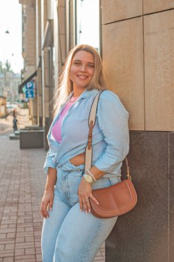 Gülümseyen Avrupalı bir model, günlük giysiler içinde, şehir arkasında. Oldukça hoş, tombul bir kadın.