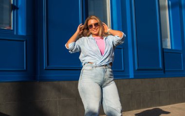 Gülümseyen Avrupalı bir model, günlük giysiler içinde, şehir arkasında. Oldukça hoş, tombul bir kadın.