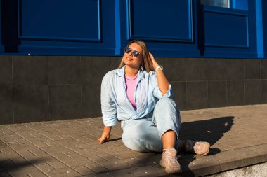 Gülümseyen Avrupalı bir model, günlük giysiler içinde, şehir arkasında. Oldukça hoş, tombul bir kadın.