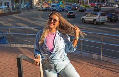 Gülümseyen Avrupalı bir model, günlük giysiler içinde, şehir arkasında. Oldukça hoş, tombul bir kadın.