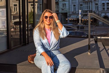 Gülümseyen Avrupalı bir model, günlük giysiler içinde, şehir arkasında. Oldukça hoş, tombul bir kadın.