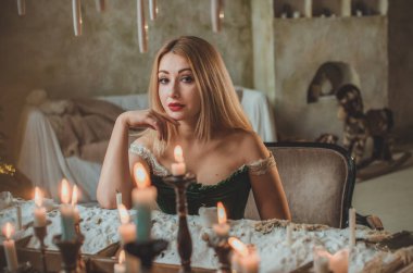 Yeni yıl atmosferi. Vintage elementler ve dekorasyon. Ortaçağ kıyafetleriyle kutlama yapan bir kadın, etrafta mumlar, havada sihir