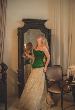 Ortaçağ korsesi ve süslü gece elbisesi giymiş, mumlar yakılmış, havada sihir var.