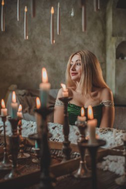 Tatil günlerindeki sarışın güzel bayan Noel atmosferi, parti havası. Yeşil ve bej elementli süslü elbiseli genç bayan. 