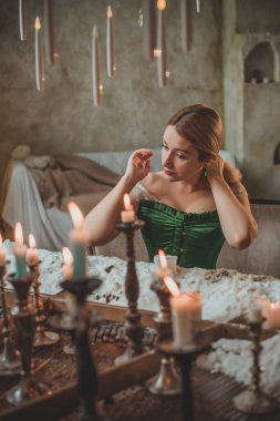 Tatil günlerindeki sarışın güzel bayan Noel atmosferi, parti havası. Yeşil ve bej elementli süslü elbiseli genç bayan. 