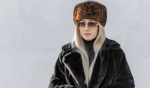 Slavic bimbo aesthetic. Portrait of a European type Blond head Young woman with natural skin in fur unisex hat.