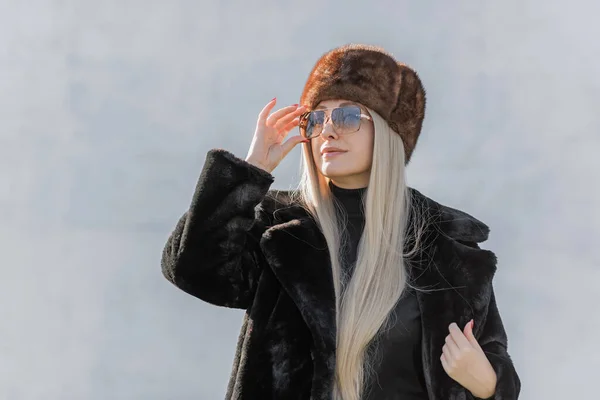 Slavic bimbo aesthetic. Portrait of a European type Blond head Young woman with natural skin in fur unisex hat.