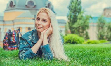 Genç Avrupalı sarışın kız şehir parkındaki çimlerin üzerinde yorucu bir günün ardından dinleniyor. Gençlik psikolojisi kavramı