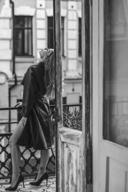 Bahar - Sonbahar koleksiyonu. Şehrin arka planında deri ceketli sarışın bir kadın. Modern klasik kadın kıyafetleri.