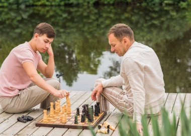 Genç yakışıklı Avrupalı adam ve babası satranç oynuyorlar, gençlik hayatı. Parkta portre