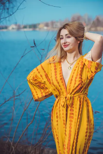 Woman in yellow cotton dress and golden accessorize like a sun. Natural women's beauty without retouch, nature background